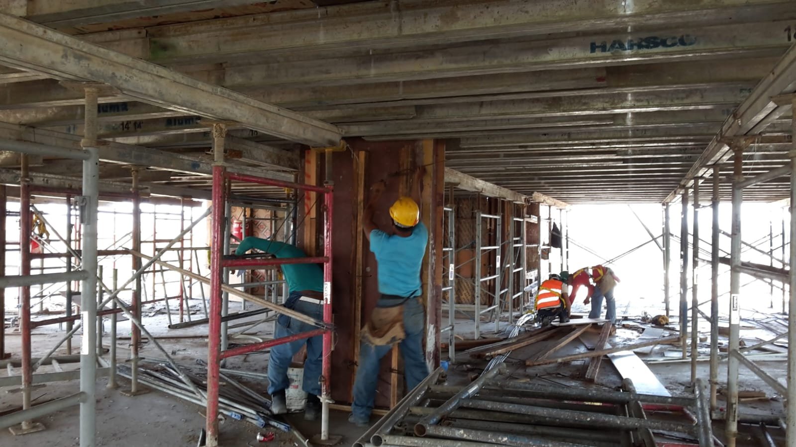 Trabajadores encofrando muros bajo losa con puntales